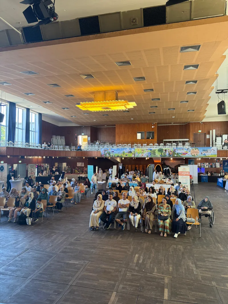 Besucherinnen und Besucher sitzen in Stuhlreihen und verfolgen das Bühnenprogramm