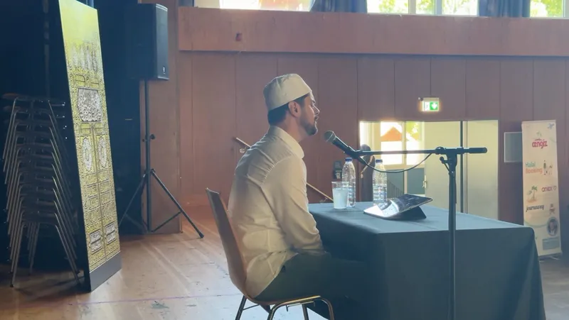 Referent mit Mikrofon an einem Tisch auf der Bühne