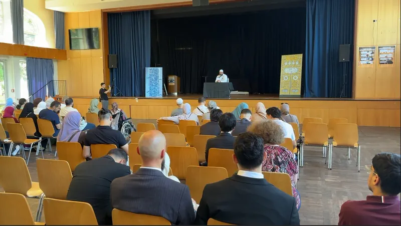 Besucherinnen und Besucher verfolgen einen Vortrag im Saal