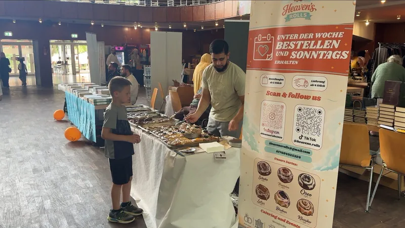 Ausstellerstand mit frischem Gebäck und Aufsteller vor dem Publikum