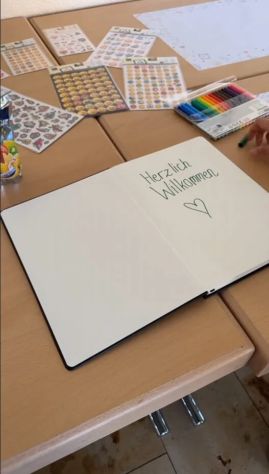 Gästebuch mit dem Schriftzug „Herzlich Willkommen" und Aufklebern